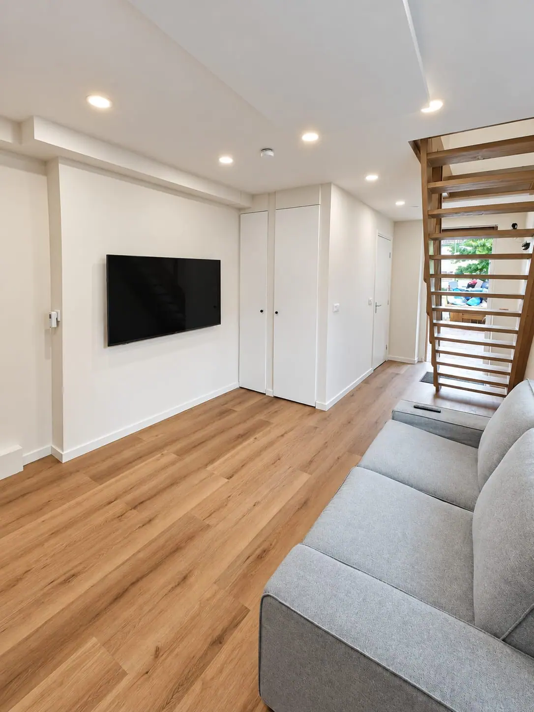 Woonkamer met houten vloer en wandtelevisie